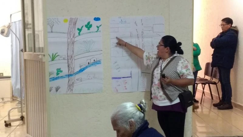 Woman pointing to large piece of paper on wall as part of workshop activity