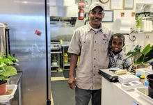 Weldy Gezehen and child in commercial kitchen