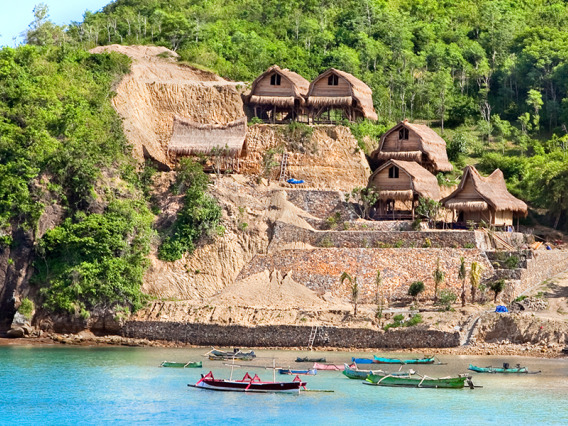 Image of human settlement and fishing boats in lush beach area.