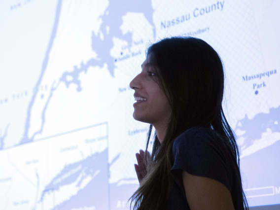 Female student presenting in front of projected map